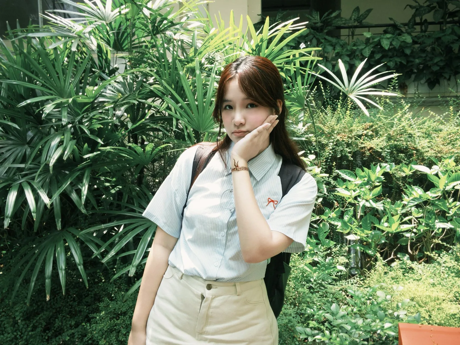 An in a light blue shirt surrounded by greenery