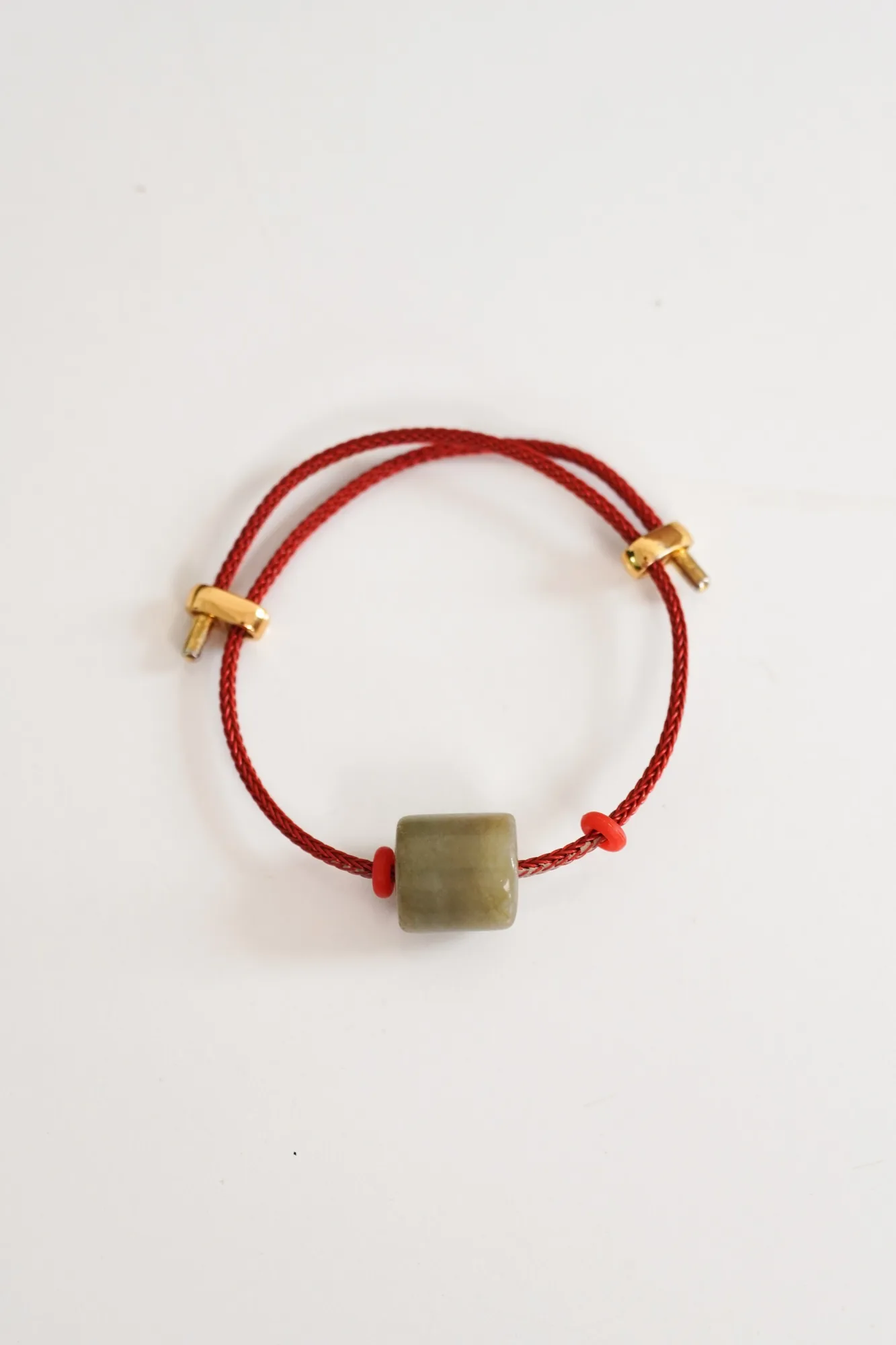 THỨC · Red cord bracelet against a pale background